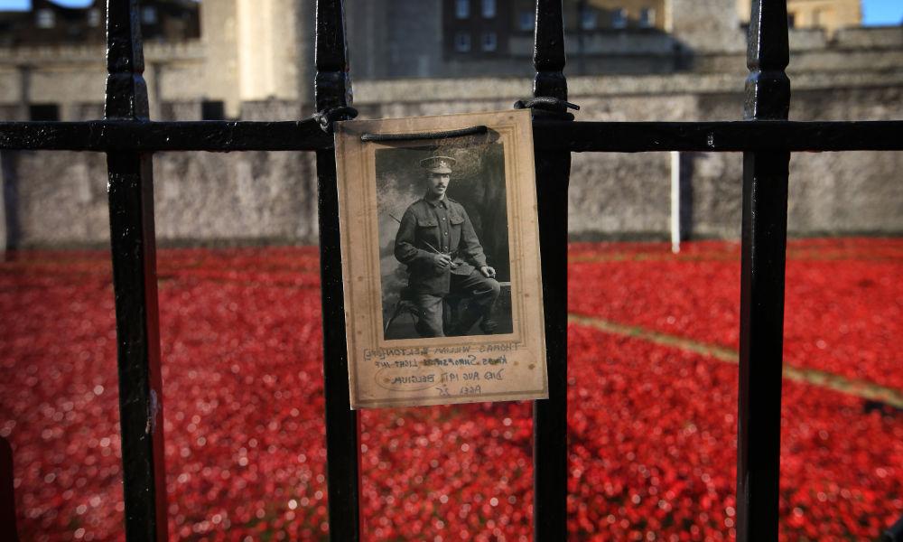 黑白照片，一名士兵被钉在大门上，前面是陶瓷罂粟花的海洋，象征着第一次世界大战的纪念.