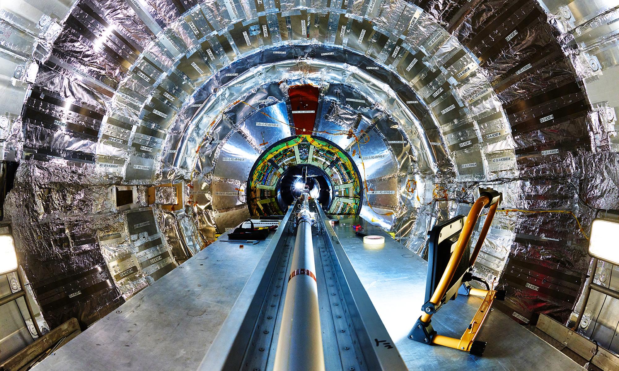 The inside of the CMS detector at CERN, showing a large central beam pipe surrounded by a silver cylinder of detectors.